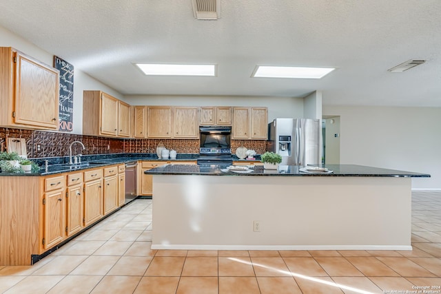 kitchen featuring a kitchen island, light tile patterned flooring, light brown cabinets, and appliances with stainless steel finishes