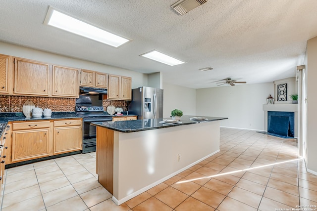 kitchen with black electric range oven, light tile patterned flooring, ceiling fan, stainless steel fridge, and a kitchen island