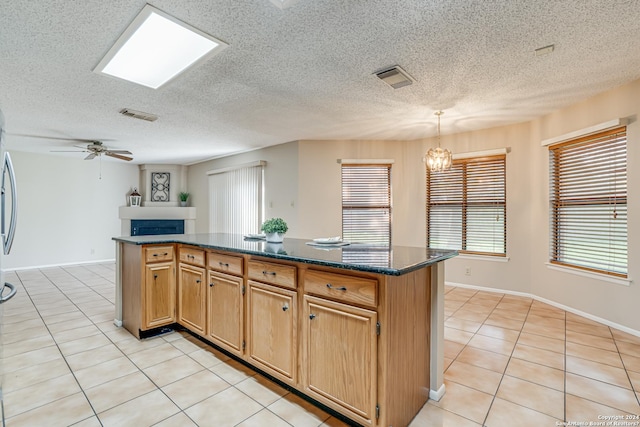 kitchen featuring ceiling fan with notable chandelier, a center island, light tile patterned floors, and decorative light fixtures