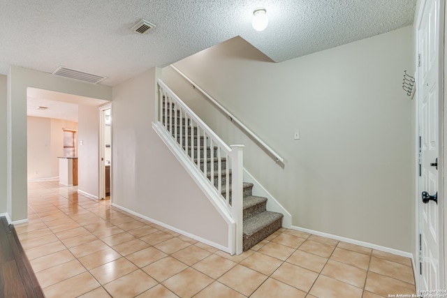 stairway with tile patterned floors and a textured ceiling