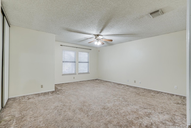 unfurnished room featuring ceiling fan, light colored carpet, and a textured ceiling