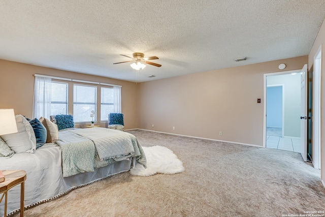 carpeted bedroom featuring ceiling fan and a textured ceiling