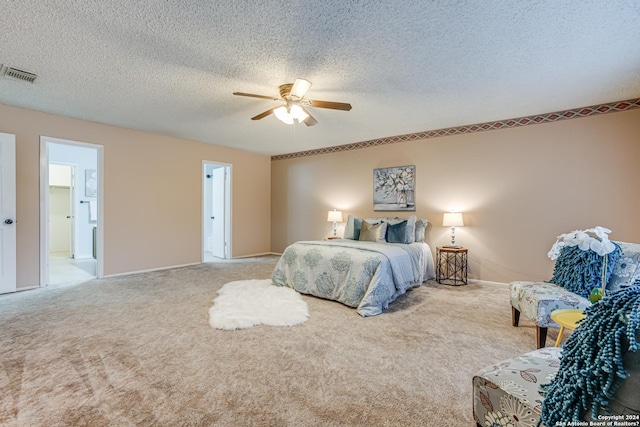 bedroom with ceiling fan, light colored carpet, and a textured ceiling