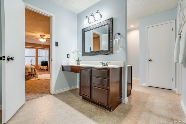 bathroom with ceiling fan, vanity, and a textured ceiling