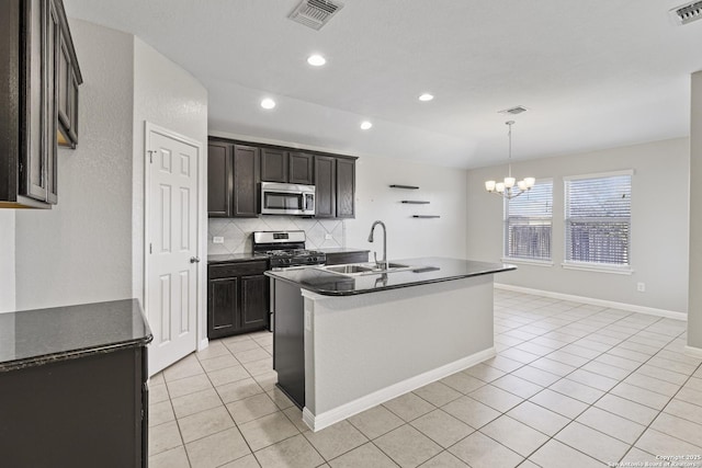 kitchen featuring sink, an island with sink, a chandelier, light tile patterned flooring, and appliances with stainless steel finishes