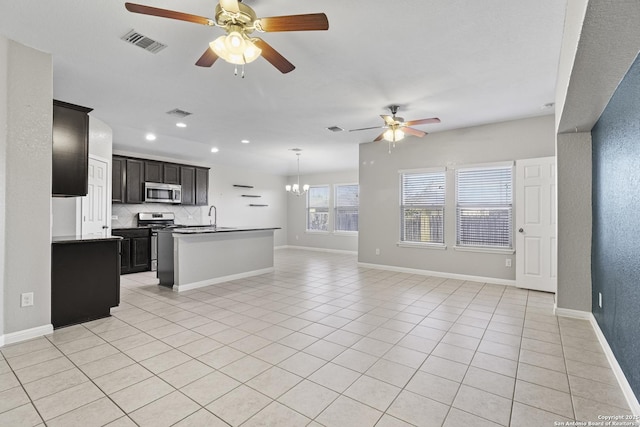 kitchen with sink, a kitchen island with sink, decorative backsplash, light tile patterned floors, and appliances with stainless steel finishes