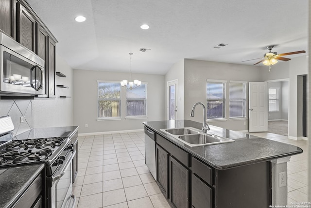 kitchen featuring ceiling fan with notable chandelier, stainless steel appliances, sink, light tile patterned floors, and an island with sink