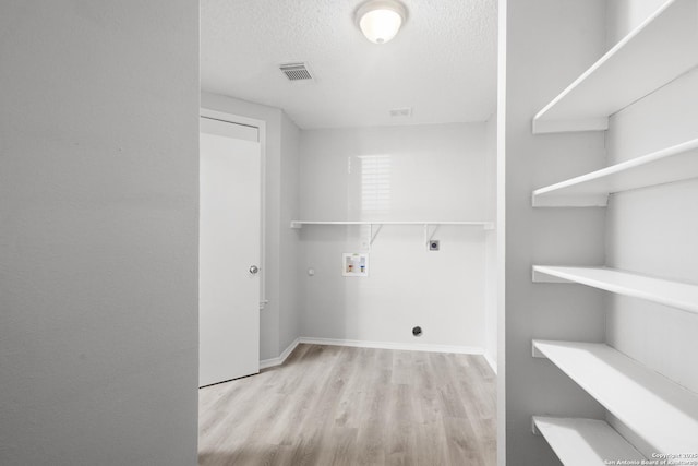 laundry area with hookup for an electric dryer, gas dryer hookup, hookup for a washing machine, light hardwood / wood-style floors, and a textured ceiling