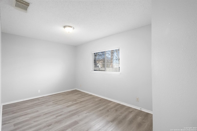 empty room featuring light hardwood / wood-style floors and a textured ceiling