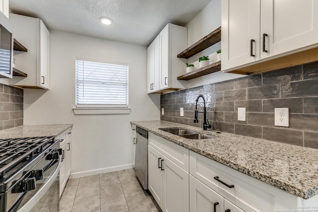 kitchen with white cabinetry, sink, light tile patterned flooring, and light stone counters