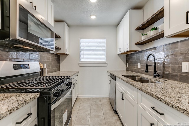 kitchen featuring white cabinetry, sink, light tile patterned flooring, and appliances with stainless steel finishes