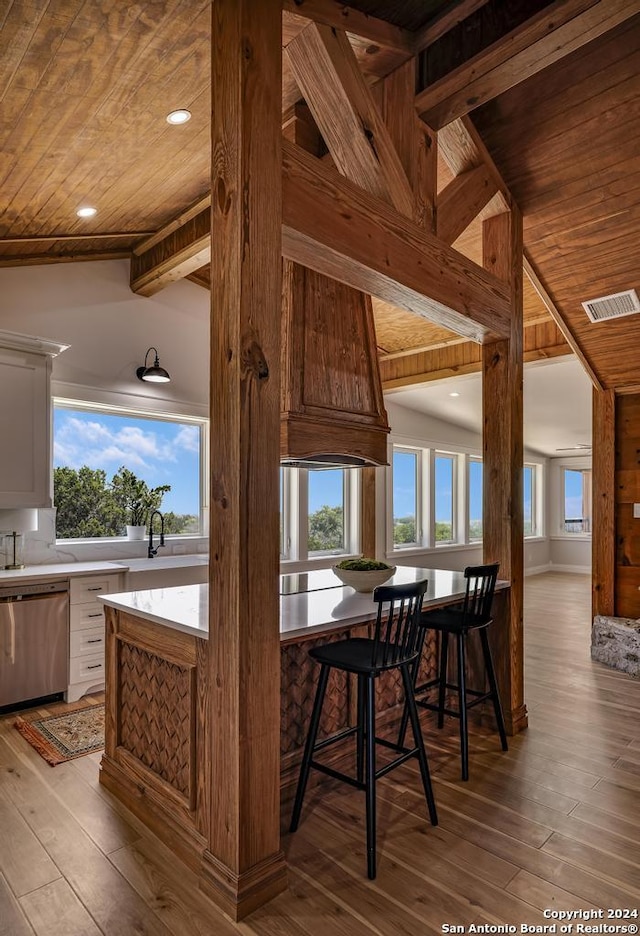 dining space with sink, lofted ceiling with beams, light hardwood / wood-style flooring, and wood ceiling