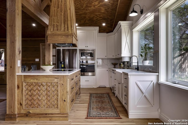 kitchen with decorative backsplash, white cabinetry, stainless steel appliances, and light hardwood / wood-style floors