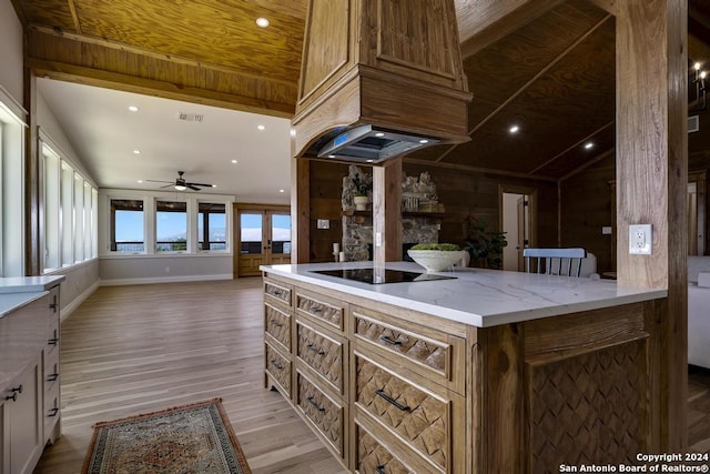 kitchen with ceiling fan, light stone countertops, light wood-type flooring, black electric cooktop, and a fireplace