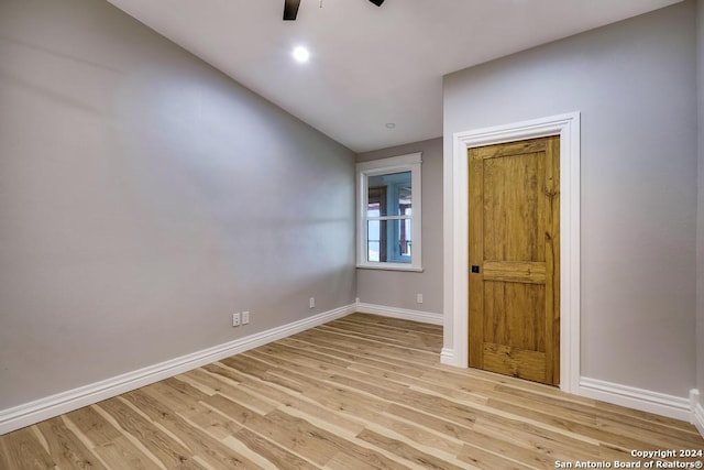 empty room with ceiling fan, vaulted ceiling, and light wood-type flooring