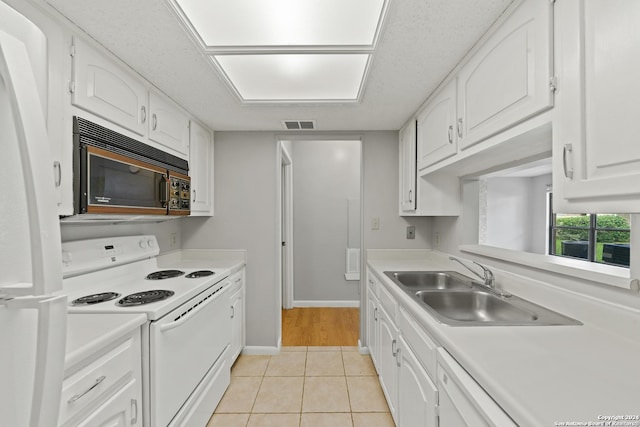 kitchen with white cabinetry, sink, light tile patterned floors, and white appliances