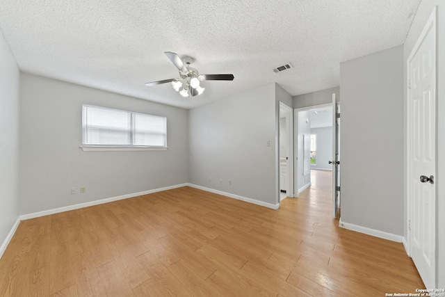 spare room featuring ceiling fan, light wood-type flooring, and a textured ceiling