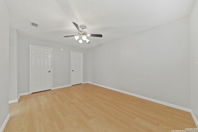 spare room with ceiling fan, light wood-type flooring, and a textured ceiling