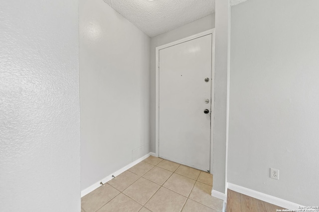 doorway to outside featuring light tile patterned flooring and a textured ceiling