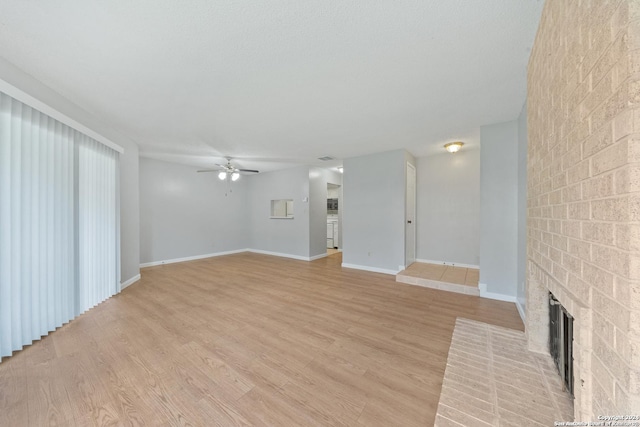 unfurnished living room with ceiling fan, a fireplace, and light hardwood / wood-style flooring