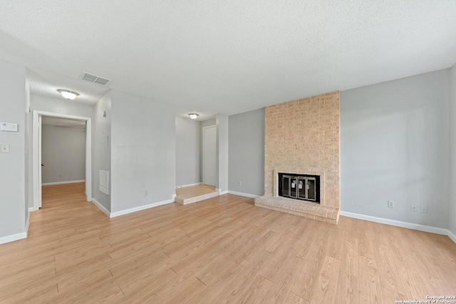 unfurnished living room featuring a fireplace, a textured ceiling, and light hardwood / wood-style flooring