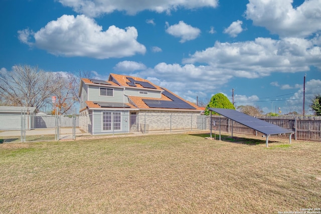 back of house with solar panels and a yard