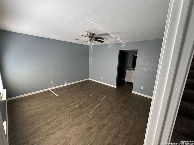 empty room with ceiling fan, dark wood-type flooring, and a textured ceiling