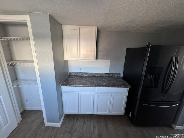 kitchen with white cabinets, stainless steel fridge, dark hardwood / wood-style flooring, and a textured ceiling