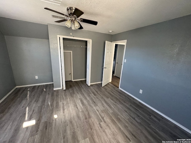 unfurnished bedroom with a closet, a textured ceiling, dark hardwood / wood-style floors, and ceiling fan