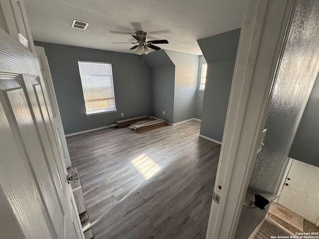 additional living space featuring dark hardwood / wood-style floors, ceiling fan, and a textured ceiling