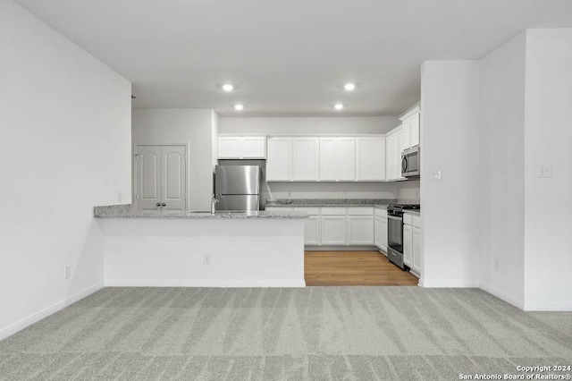 kitchen featuring light stone countertops, sink, light colored carpet, white cabinets, and appliances with stainless steel finishes