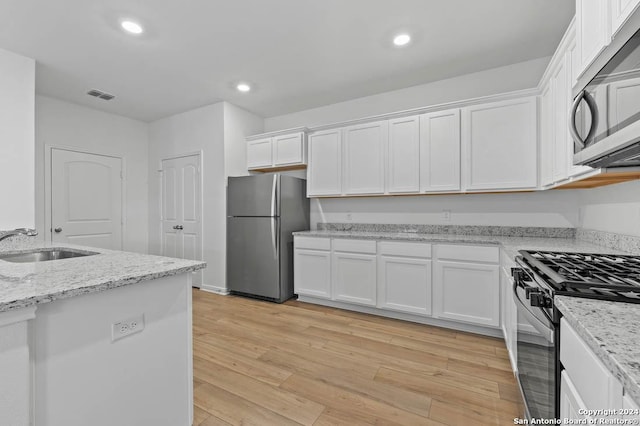 kitchen featuring light stone countertops, appliances with stainless steel finishes, sink, light hardwood / wood-style floors, and white cabinetry