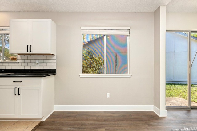 kitchen with white cabinets, decorative backsplash, a textured ceiling, and a wealth of natural light