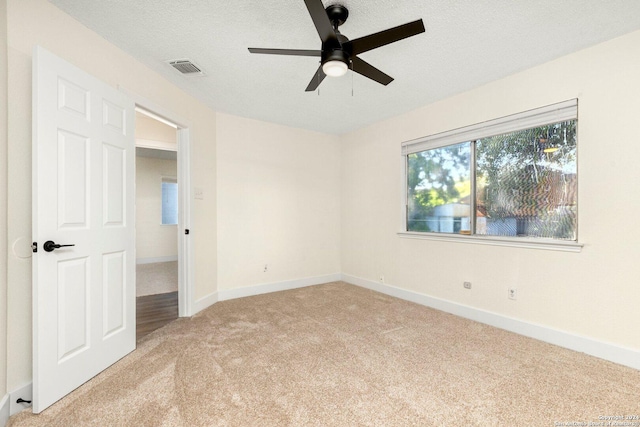 carpeted empty room featuring a textured ceiling and ceiling fan