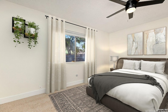 bedroom with ceiling fan, light carpet, and a textured ceiling