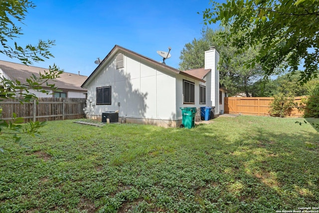 back of house with a yard and central AC