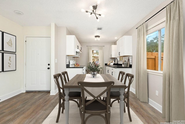 dining space featuring a healthy amount of sunlight, sink, dark wood-type flooring, and a textured ceiling