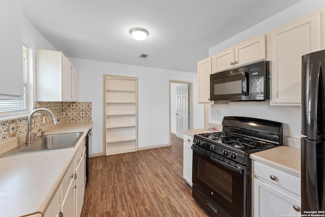 kitchen with black appliances, light hardwood / wood-style floors, white cabinets, and sink