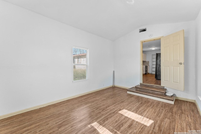 spare room featuring hardwood / wood-style floors and lofted ceiling