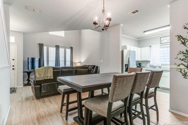 dining space with light wood-type flooring and an inviting chandelier