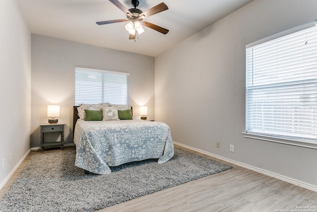 bedroom with hardwood / wood-style floors, ceiling fan, and multiple windows