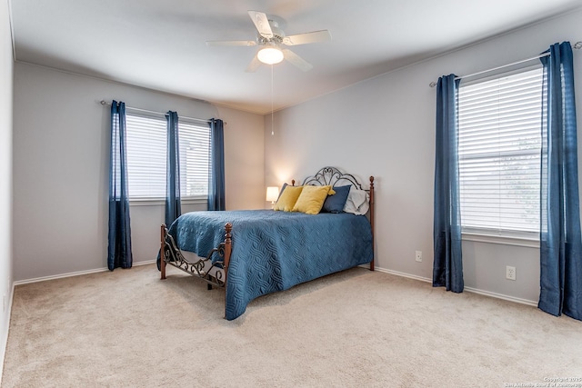 bedroom with ceiling fan, light carpet, and multiple windows