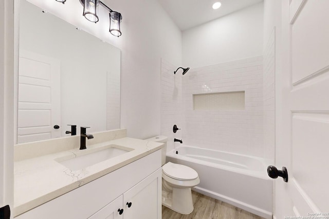 full bathroom featuring vanity, wood-type flooring, tiled shower / bath combo, and toilet