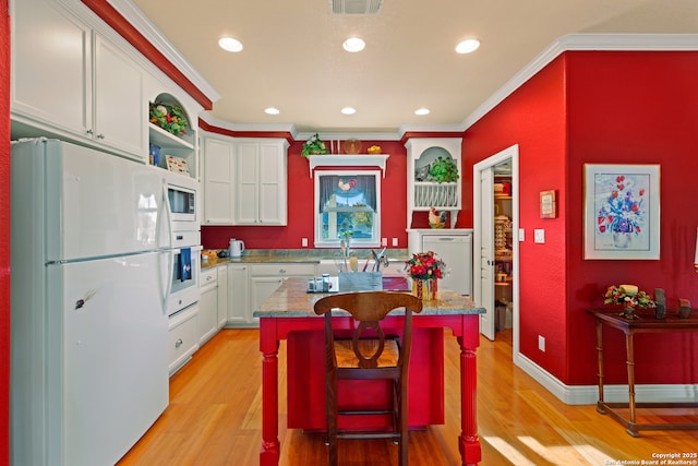 kitchen with light wood-type flooring, ornamental molding, a breakfast bar, white appliances, and a kitchen island