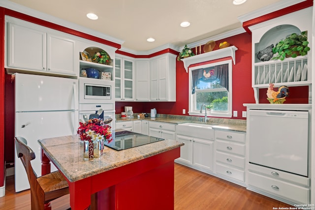 kitchen featuring white appliances, a kitchen island, light stone counters, white cabinetry, and a breakfast bar area