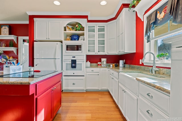 kitchen with white cabinetry, sink, light hardwood / wood-style flooring, crown molding, and white appliances