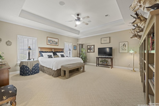 bedroom with ceiling fan, light colored carpet, and a tray ceiling