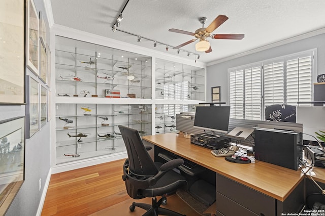 office with crown molding, rail lighting, ceiling fan, light wood-type flooring, and a textured ceiling