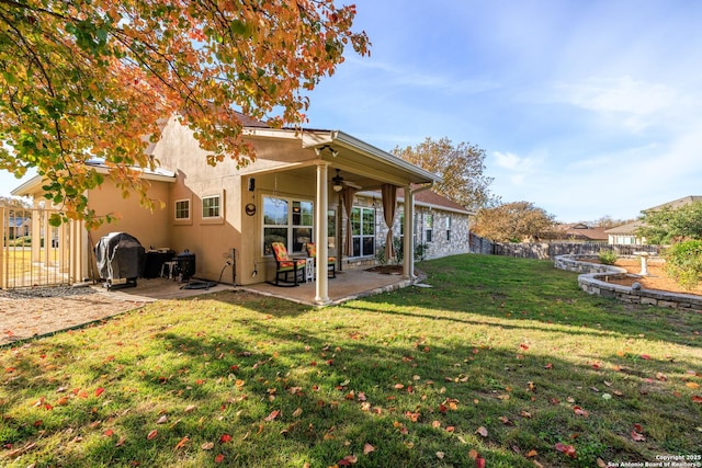 rear view of property featuring ceiling fan, a yard, and a patio