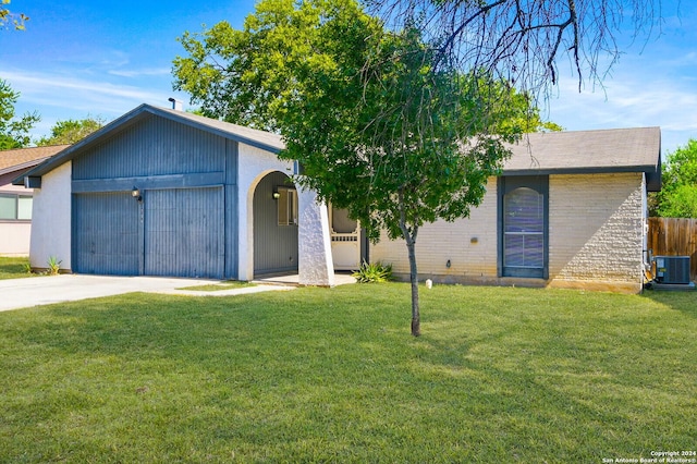 view of front of home featuring central AC unit, a garage, and a front lawn